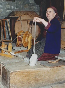 Old_woman_behind_spinning_wheel_in_Greece